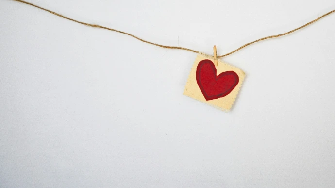 A red heart drawn on a small square card hanging from a string